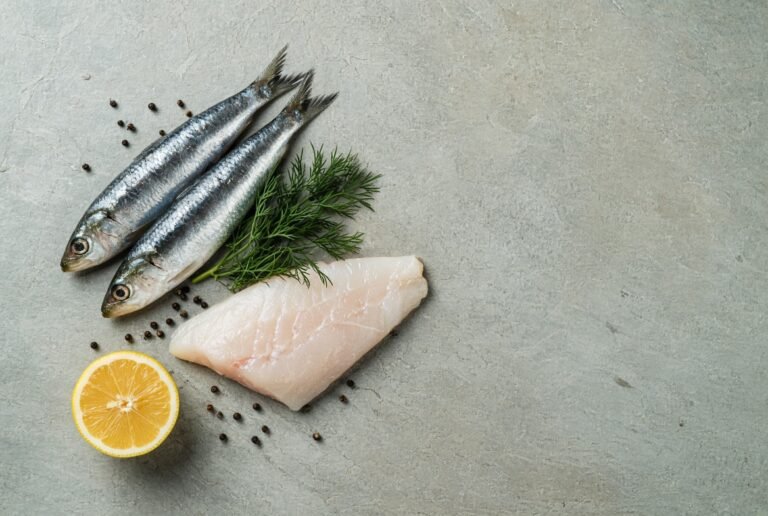 Fresh sardines and white fish fillet with dill and lemon on slate